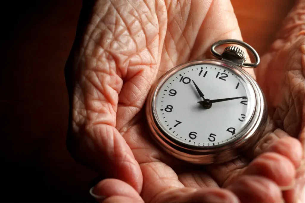 An elderly woman's hands holding a watch, illustrating the rapid aging process and the passage of time.