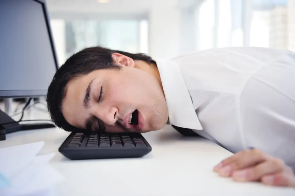 An office worker sleeps on the keyboard while doing his work.